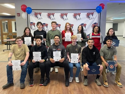 A group of student holding certificates and smiling.