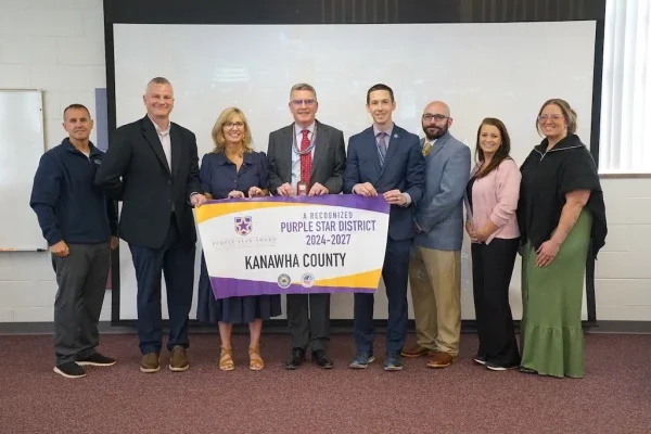 Group of people posing for a photo while holding a poster.