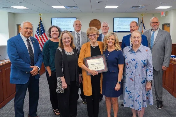 West Virginia Board of Education members surrounding Debra Sullivan. She is holding a frame.