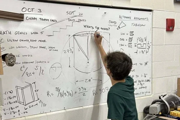 A student solving math equations on a whiteboard.