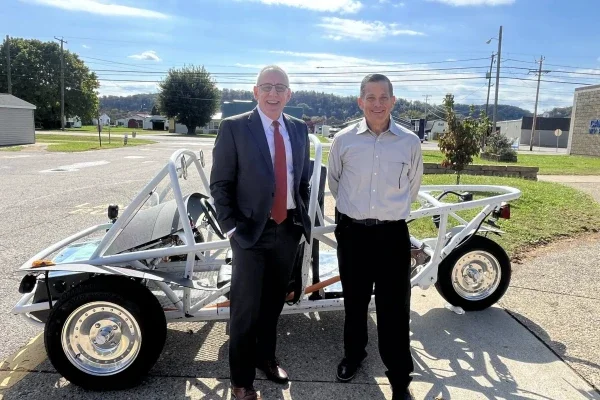 two people standing in front of a vehicle.