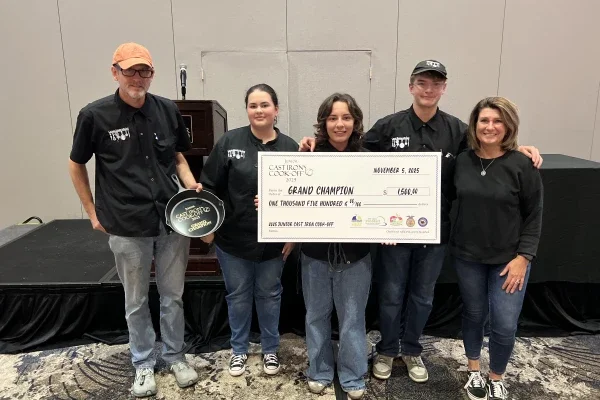A group of people holding a price check for being named grand champion