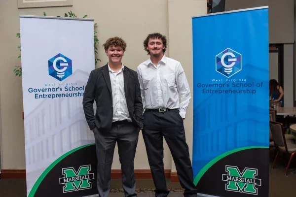 Two people standing in front of Governor's School of Entrepreneurship banners.