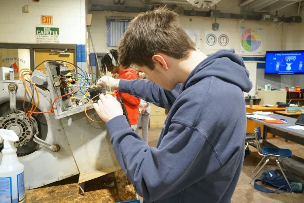 A student working with the wiring of an HVAC unit.