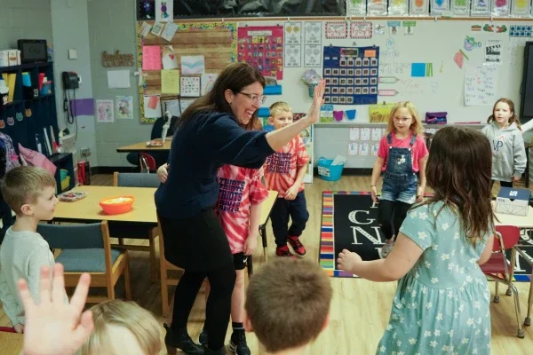 A principal giving a student a high five in a classroom.