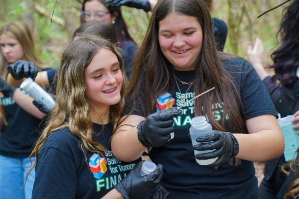 Two students smiling while looking at a bottle of water. 