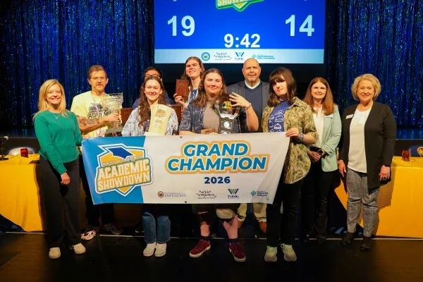Members of Morgantown High School's Academic Showdown team smiling while holding a banner and a trophy. 