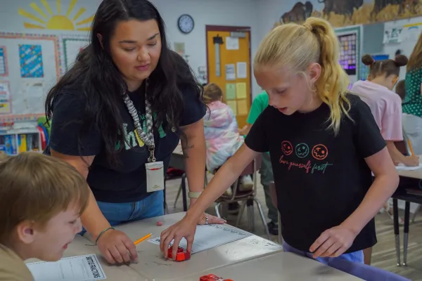 A teacher helping students in a classroom. 