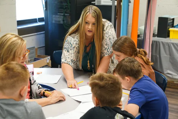 A teacher works with students on classwork