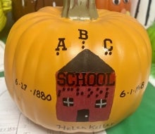 A pumpkin with a school on it along with braille letters.