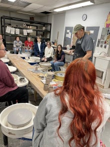 A group of people watching someone teach art.