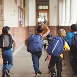 Five elementary students walking down the hallway