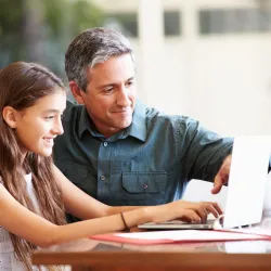 Father helping his daughter with laptop