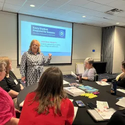 Dr. White speaks to educators sitting at a table.