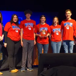 Team of students standing together with an award.
