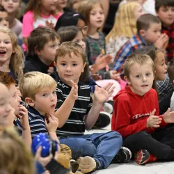 Children gather on the floor for a school assembly.