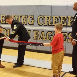 Children learning to fold a flag at a speaker series event.