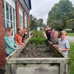 Students standing around a bed of soil for a Farm to School project.