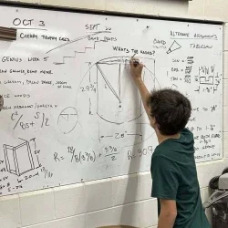 A student solving math equations on a whiteboard.