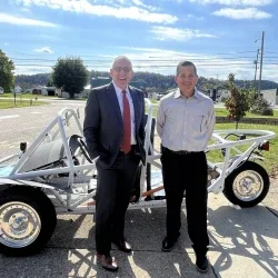two people standing in front of a vehicle.