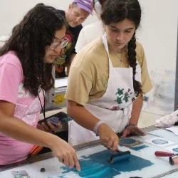 Two female students preparing ink for use in a printmaking exercise in a art room.