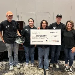 A group of people holding a price check for being named grand champion
