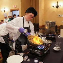 A student cooking something in a pan.