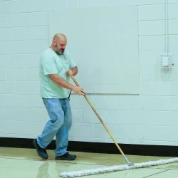 Brandon Kelley holding a broom and sweeping the floor.