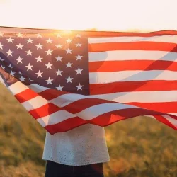 Woman holding American flag in a grassy field