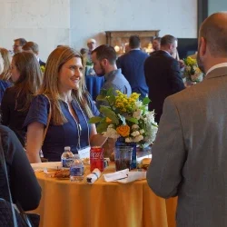 People standing at a table enjoying refreshments, talking, and laughing