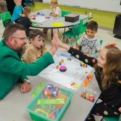 Justin Endicott giving a student a high five while other students watch.