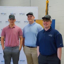 Three students smiling while wearing Hope Gas hats.