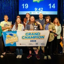 Members of Morgantown High School's Academic Showdown team smiling while holding a banner and a trophy. 