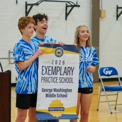 Students smiling while holding an Exemplary Practice School banner. 
