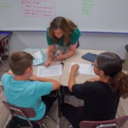 An adult helping students with their work. 