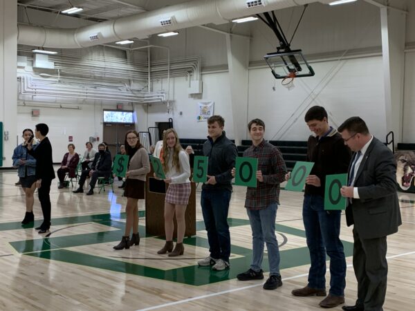 State Superintendent of Schools W. Clayton Burch joins East Hardy High School students as they hold cards designating the financial award Wolfe receives as part of the Milken program.