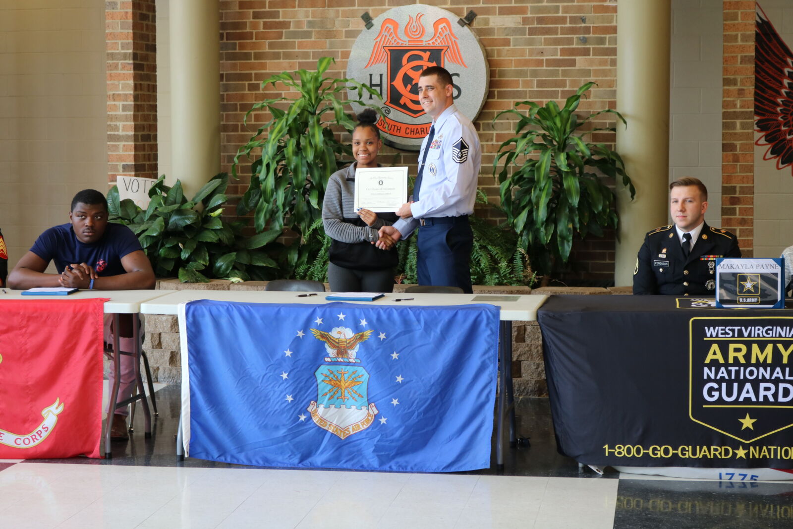 Student shaking hands on stage with member of military after participating in military signing event.